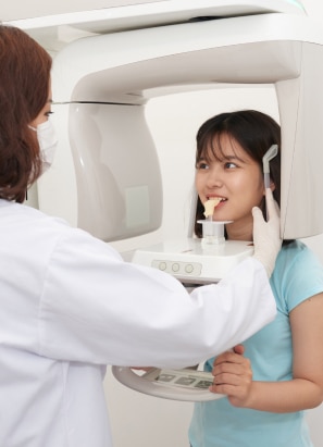 Young person standing in CBCT scanner getting their mouth scanned.