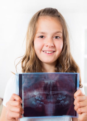 Young person holding up dental x-ray.