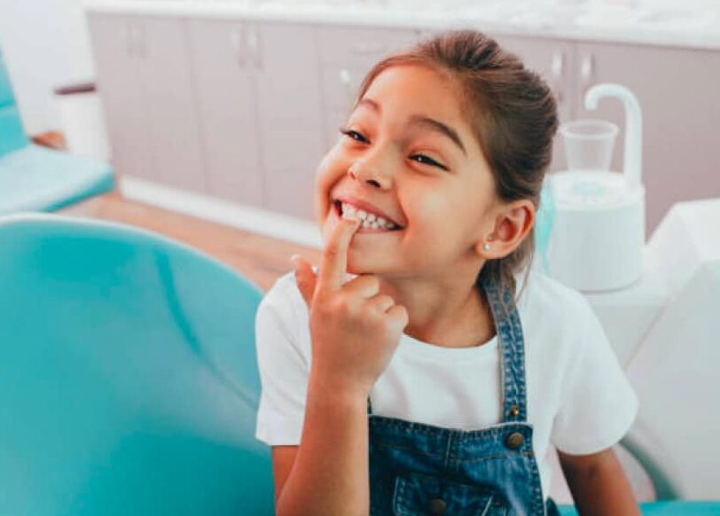 Young girl pointing to her teeth at dentist office.